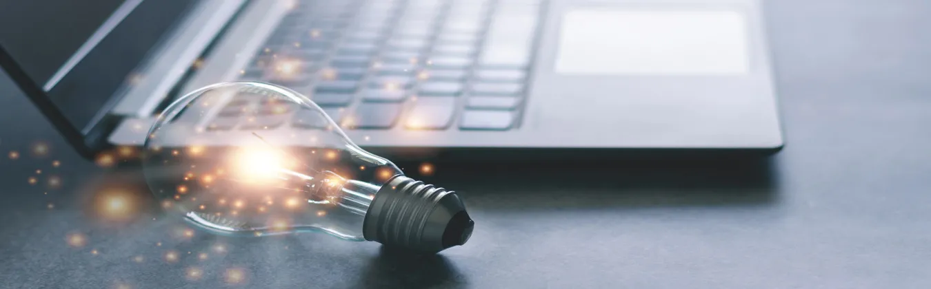 Lightbulb lit up beside a laptop